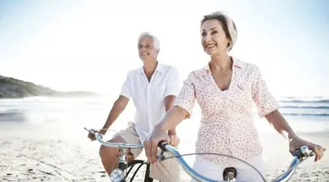 Retired couple biking along the beach