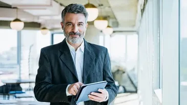 A business professional holding a tablet in a modern office