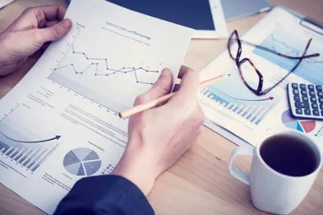 A tax planner reviewing charts with a calculator and financial statements on a desk