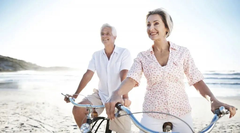 Retired couple biking along the beach