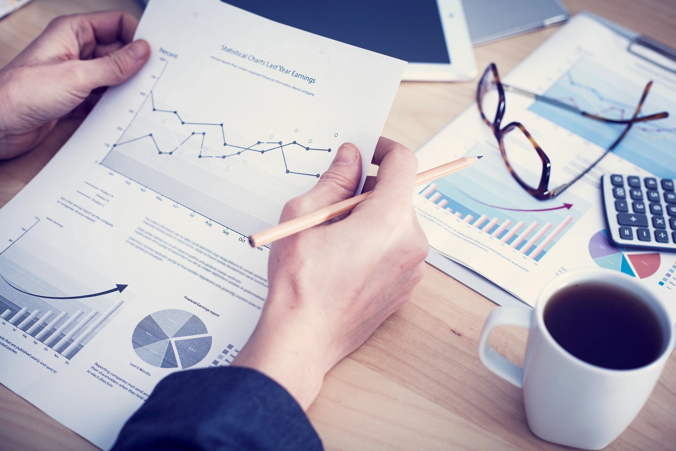 A tax planner reviewing charts with a calculator and financial statements on a desk